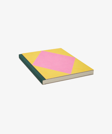 Dreamer's Notebook. Rectangular book with yellow background, pink diamond, and navy bound spine, angled flat view.