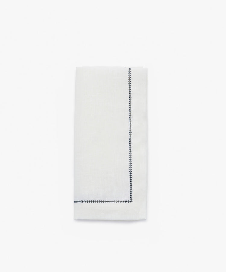 Single Lorna Hemstitch Napkin in white linen with dark blue stitching.